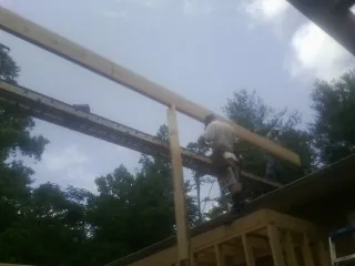 Carpenter setting a ridge beam over a new addition frame in Tampa