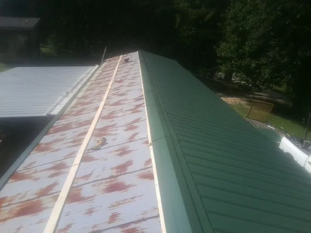 Old rusted panels beside newly installed green metal roofing — Wind Damage Roof Repair by Roofing Brothers in Tampa