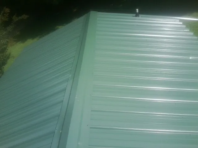 New green metal panels meeting at the ridge of a roof — Flat Roof Repair work by our crew in Tampa