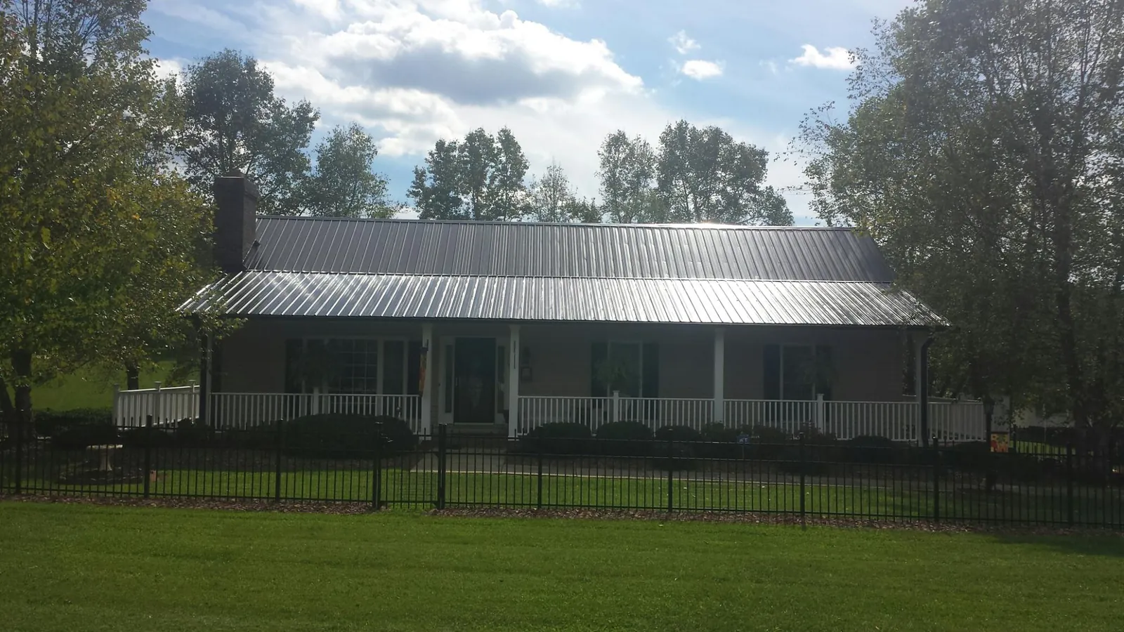 Gray metal roof on a brick ranch with a full width front porch — Gutter Guard Installation work by our crew in Tampa