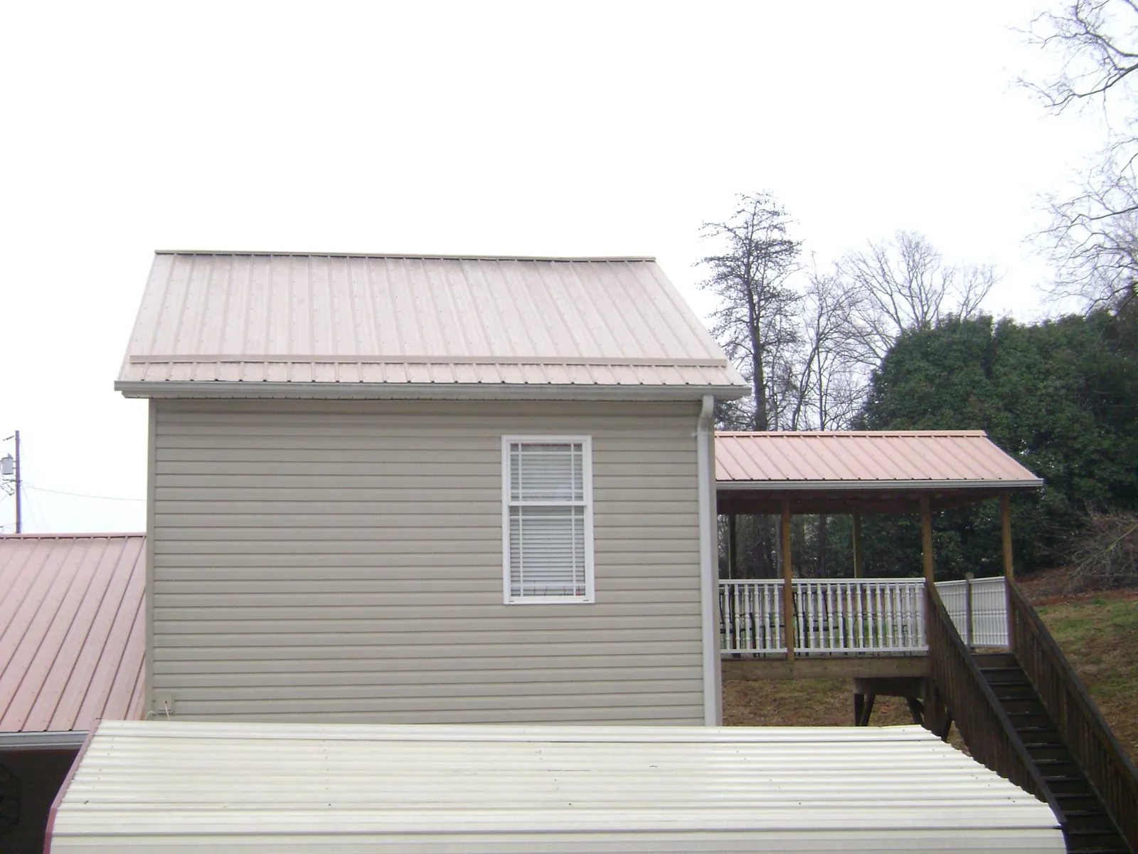 Tan metal roofs on a two story addition and attached porch, from a Roof Replacement job in Tampa