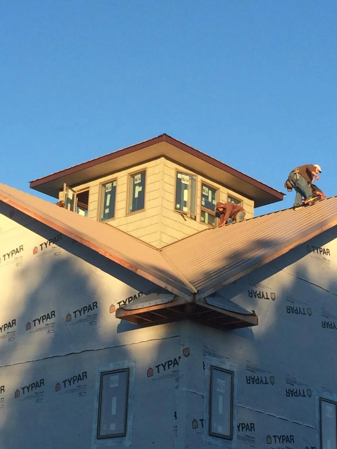 Roofers working around a rooftop cupola on a new metal roof at sunset — Roof Waterproofing in Tampa by Roofing Brothers